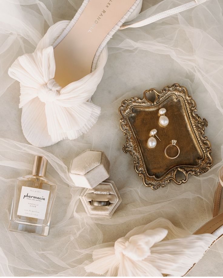 Elegant neutral wedding flat lay with invitation suite, ivory ribbon, and gold rings. 