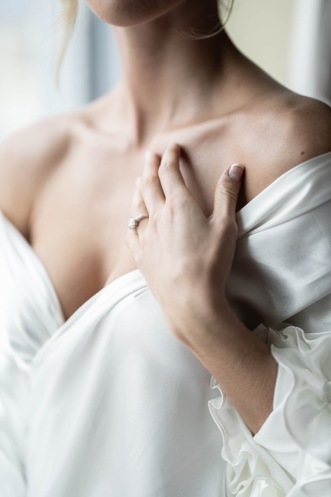 Close-up of bride’s chest and jewelry while getting dressed on wedding day
