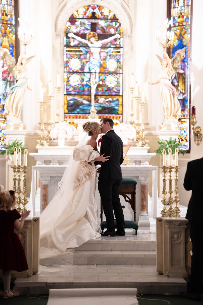 Bride and groom sharing a kiss at the altar of St. Patrick’s Cathedral in Fort Worth, Texas