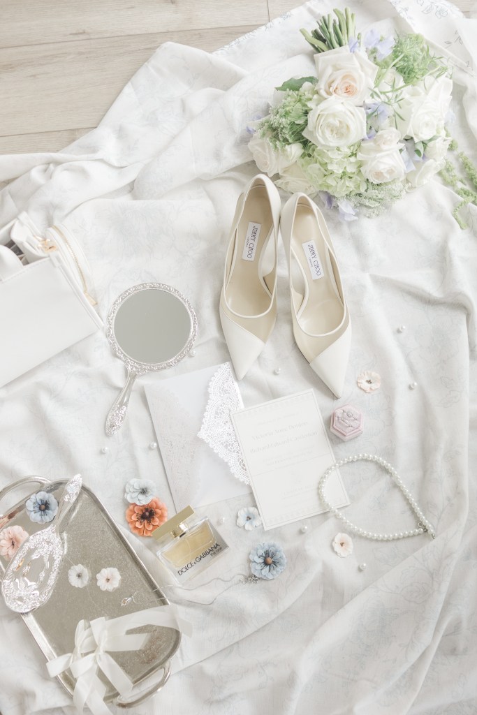 Detailed flat lay of wedding stationary with dusty blue accents and vintage stamps. 