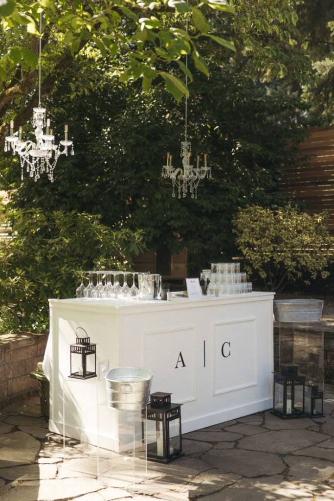 Elegant white garden wedding bar with the couple’s initials displayed on the front