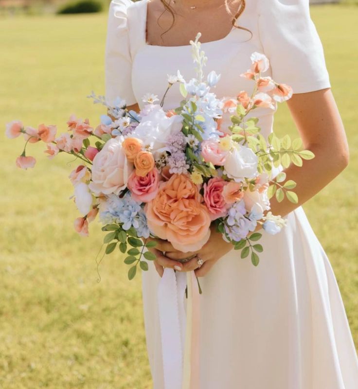 Bride holding a pastel wedding bouquet, symbolizing a timeless and personal wedding color choice.